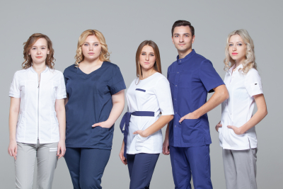 team of caregivers looking at camera while standing on grey background