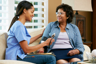 nurse visiting senior female patient at home smiling